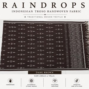 Puede incluir: Un tejido marrón oscuro hecho a mano con un patrón geométrico repetitivo de pequeños diamantes blancos. La tela incluye un borde decorativo con intrincadas líneas blancas y flecos, con unas dimensiones de 230cm por 115cm.