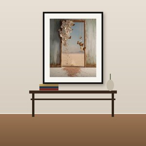 May include: A framed wall art print featuring a surreal doorway opening to a desert landscape. White floral clusters cascade from the top corner, while brown butterflies float near the frame. A trail of petals covers the floor in the foreground.