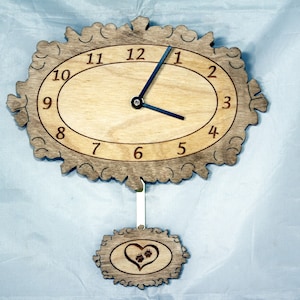 May include: Wooden wall clock with an oval face and decorative frame. The clock features black hands and numbers, with a heart and paw print design on the pendulum. The clock is made of light brown wood.
