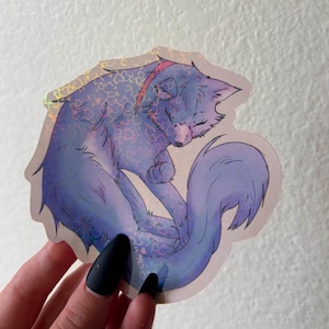 Puede incluir: Una pegatina troquelada que muestra un gato acurrucado con tonos de pelaje morado y azul. La ilustraci&oacute;n tiene un acabado hologr&aacute;fico con un patr&oacute;n repetitivo de peque&ntilde;os corazones visible en el cuerpo del gato y su larga cola esponjosa.