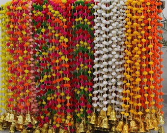 May include: A collection of decorative hanging garlands featuring strings of small, colorful pom-poms in shades of yellow, pink, red, green, white, and orange, each finished with a small, metallic gold-toned bell at the bottom end.