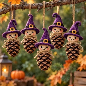 May include: Five hanging ornaments featuring crocheted witch heads with purple hats, yellow buckles, and rosy cheeks, each attached to a natural brown pinecone body with a jute twine loop for suspension, creating a set of seasonal decorations.