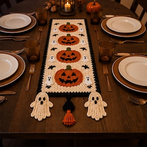 Peut inclure: Un chemin de table rectangulaire en crochet orné de quatre citrouilles orange à tiges vertes, entourées de petits fantômes blancs et de chauves-souris noires sur fond crème. Il présente une bordure noire et deux grands motifs de fantômes.