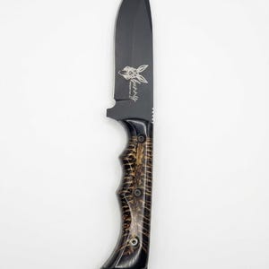 May include: A fixed-blade knife with a matte black finish on the blade and a dark, textured wood handle. The blade features an engraved graphic of a rabbit head and the text "bunny" in a script font. The handle is secured with three metal rivets.