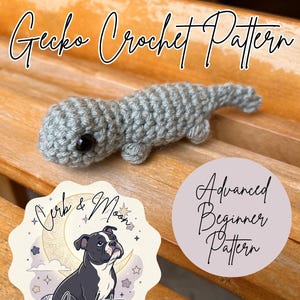 Op de afbeelding: Een kleine, lichtgrijze gehaakte gekko met een ronde kop, een zwart plastic oog en een getextureerd lichaam. De afbeelding bevat de tekst Gecko Crochet Pattern en Advanced Beginner Pattern, samen met een logo met een hond en de tekst Orb & Moon Crochet.