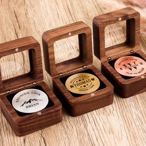May include: Three square wooden boxes with hinged glass lids, each containing a circular metal decision coin. The coins are silver, gold, and copper-colored, engraved with names Brian, Thomas, and William, along with decision-making text.