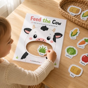Puede incluir: Una hoja de actividades Feed the Cow con una ilustración de una vaca blanca con una boca grande recortada. La hoja incluye varios recortes de comida etiquetados como Hay, Corn, Carrot, Lettuce, Apple y Grass. El texto dice Feed the Cow y LittleMuseShop.