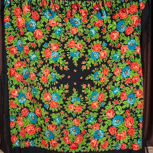 Könnte beinhalten: Ein schwarzer Schal mit einem Blumenmuster mit roten, blauen und grünen Blumen. Der Schal hat einen Fransenrand.