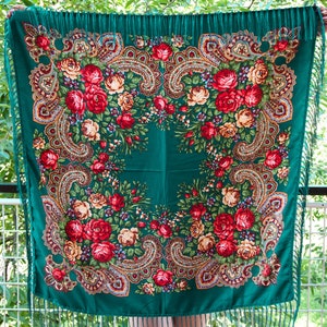 Könnte beinhalten: Ein grüner Schal mit Blumenmuster und Fransen. Der Schal hat ein Paisley-Muster mit roten, weißen und gelben Blumen.