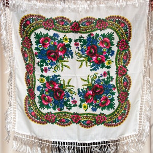 Peut inclure: Écharpe en coton blanc avec un motif floral. Le motif présente des fleurs rouges, roses, jaunes, bleues et vertes. L'écharpe a une bordure en frange blanche.