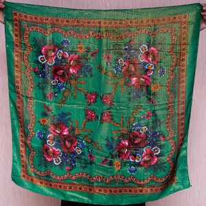 Puede incluir: Un pañuelo de seda verde con un borde dorado y un patrón floral. Las flores son rojas, rosas, azules y amarillas.
