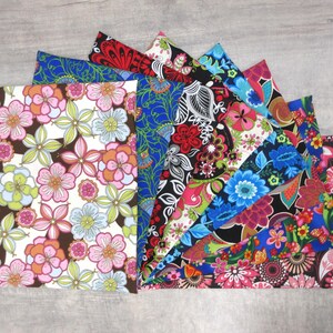 May include: A collection of colorful floral fabric swatches. The fabrics feature various patterns with flowers in shades of pink, blue, red, and green on white, black, and brown backgrounds. The swatches are arranged in a fan shape.