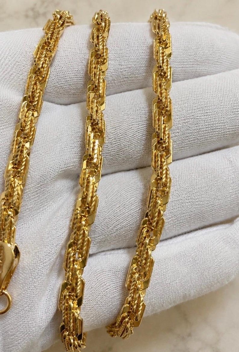 May include: A gold chain necklace featuring a complex, multi-link design with alternating smooth, rectangular segments and twisted, rope-like sections. The metallic yellow finish has a high-shine, reflective surface throughout the entire length.
