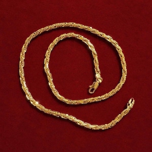 May include: A gold chain necklace featuring a textured, interlocking link design. The chain is arranged in a circular pattern and includes a secure lobster claw clasp mechanism at one end, showcasing a polished, reflective metallic finish throughout.