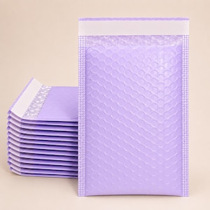 May include: A stack of rectangular lavender bubble mailers featuring a textured surface with circular air pockets and a white adhesive strip at the top edge for sealing. The mailers are constructed from a lightweight, flexible material.
