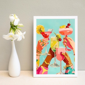 Peut inclure: Une impression d'art encadrée représentant une illustration colorée de quatre mains tenant divers cocktails avec des garnitures comme des cerises et des tranches d'agrumes sur fond bleu clair, exposée à côté d'un vase blanc avec des fleurs blanches.