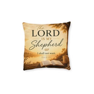Peut inclure: Un coussin carré décoré d'un paysage aux tons dorés représentant un lac au coucher du soleil. Le texte indique : The LORD IS MY Shepherd I shall not want. PSALM 23:1. Un livre ouvert et une petite tasse sont posés sur une surface en bois.