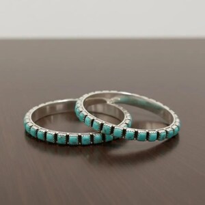 Puede incluir: Dos brazaletes circulares de plata con una incrustaci&oacute;n continua de peque&ntilde;as piedras de turquesa de corte cuadrado. Cada pulsera tiene un marco de metal pulido con un dise&ntilde;o de borde dentado que asegura las piedras azul-verdosas.