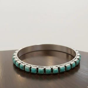 Puede incluir: Un brazalete de plata con una hilera continua de peque&ntilde;as piedras de turquesa de corte cuadrado engastadas en biseles met&aacute;licos individuales. La pulsera tiene un acabado met&aacute;lico pulido y una forma circular uniforme con un patr&oacute;n repetitivo.
