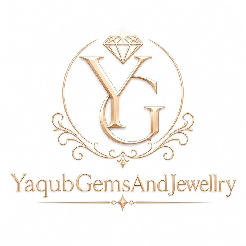 Puede incluir: Un logotipo de color dorado que presenta las letras YG entrelazadas dentro de un marco circular, rematado con un icono de diamante y adornos decorativos. Debajo del emblema, el texto YaqubGemsAndJewellry est&aacute; escrito en fuente serif.