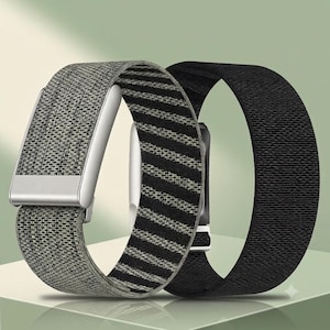 May include: Two elastic watch bands for a smartwatch. One band features a textured gray and black striped pattern with a silver-toned metal buckle. The second band is a solid black, woven fabric strap with a simple, continuous loop design.