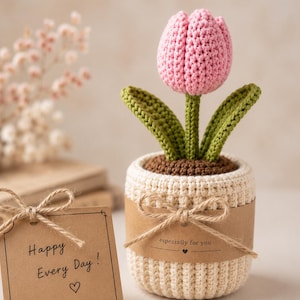 May include: A crocheted pink tulip with green leaves planted in a cream-colored pot. The pot is wrapped in a brown paper band tied with twine, featuring the text "especially for you" and a heart. A matching brown tag reads "Happy Every Day!" with a heart.