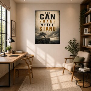 Pode incluir: Uma impressão de arte retangular com uma árvore solitária num penhasco sob um céu nublado. O texto diz YOU CAN SHAKE AND STILL STAND em letras pretas e douradas. O design tem uma estética envelhecida com uma borda escura.