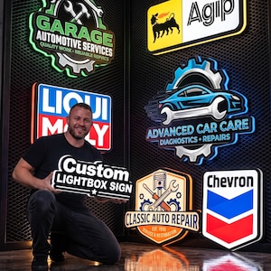 May include: A collection of illuminated wall-mounted signs featuring automotive branding and repair shop logos. The signs include Garage Automotive Services, Agip, Liqui Moly, Advanced Car Care, Classic Auto Repair, Chevron, and a Custom Lightbox Sign.