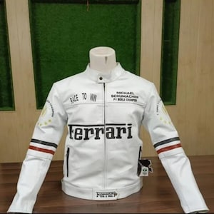 Könnte beinhalten: Eine weiße Jacke mit schwarzem Text, der Race to Win und Michael Schumacher F-1 World Champion lautet. Die Vorderseite zeigt das Ferrari-Logo in Schwarz, mit roten und schwarzen horizontalen Streifen an den Ärmeln und einem Ferrari-Logo am Saum.
