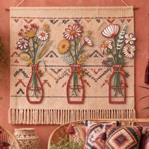 Pode incluir: Uma tapeçaria de parede com três recortes de vasos vermelhos e arranjos florais. Os vasos apresentam as palavras I, LOVE e YOU. As flores, em vermelho, branco e amarelo, estão sobrepostas a um tecido creme com um padrão geométrico.