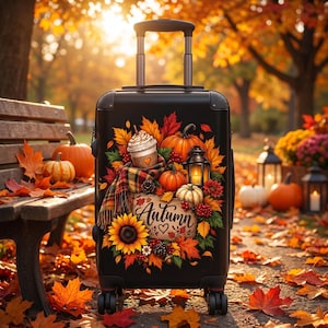 May include: A black rolling suitcase featuring a colorful graphic print of pumpkins, autumn leaves, a sunflower, a plaid scarf, a coffee cup, a lantern, and a sign with the word Autumn written in cursive script with a small heart symbol below it.