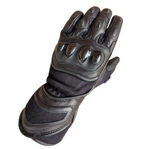 Puede incluir: Un guante de moto negro con protector de nudillos reforzado, tapas protectoras en los dedos y un puño largo. El guante está fabricado con una combinación de cuero y materiales textiles, con paneles cosidos y un cierre en la muñeca.