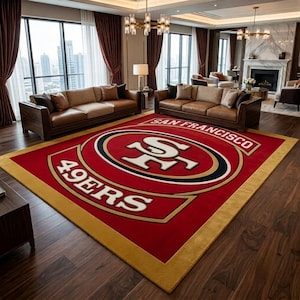 Könnte beinhalten: Ein rechteckiger Teppich mit dem Logo der San Francisco 49ers in Rot, Gold, Weiß und Schwarz. Das Design zeigt den Teamnamen San Francisco und 49ers in fetter Schrift, zentriert auf einem leuchtend roten Hintergrund mit goldenem Rand.