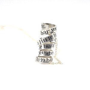 May include: Silver necklace with a spiral design featuring the words "You don't have to be huge to do brave things. A little bit of brave can change everything."