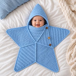 以下が含まれることがあります： 星の形をした水色のクロシェ編みのベビー用おくるみで、とがったフードが付いています。この衣類は質感のあるニットパターンが特徴で、サイドフラップに沿って3つの小さな茶色の木製ボタンが付いており、赤ちゃんを包み込むデザインになっています。
