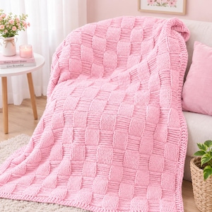 May include: A soft, light pink chunky knit throw blanket featuring a prominent basketweave pattern. The blanket is constructed from thick yarn, creating a textured, square-grid design throughout the entire surface of the fabric.