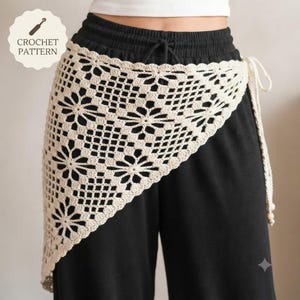 Könnte beinhalten: Ein beigefarbener Häkel-Wickelrock mit einem sich wiederholenden Blumenmuster und einem Gitterdesign. Das Kleidungsstück hat einen gewellten Rand und einen langen Bindegürtel mit einer kleinen Perle am Ende. Der Text CROCHET PATTERN ist oben zu sehen.