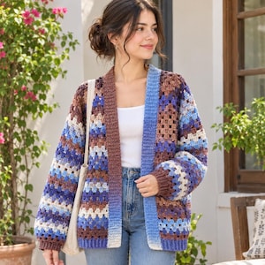 May include: A long-sleeve crochet cardigan featuring a granny square pattern in shades of brown, blue, and white. The garment has a solid brown ribbed trim along the front opening and cuffs, a relaxed fit, and a white tank top worn underneath.