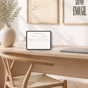 May include: A black tablet displaying a digital document titled THE MASSIVE COVERAGE SHEET with various blank fields, lines, and sections for data entry, positioned on a light wood desk next to a closed silver laptop computer.