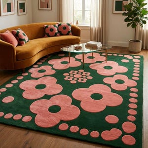 May include: A rectangular area rug featuring a deep forest green background with a repeating pattern of large, soft pink stylised flowers and smaller pink circular dots arranged in a border and a central cluster on the surface of the rug.