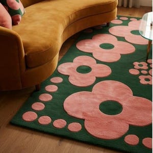 May include: A rectangular area rug featuring a deep forest green background with a repeating pattern of large, soft pink four-petaled flowers and smaller pink circular dots arranged in clusters across the surface of the floor covering.