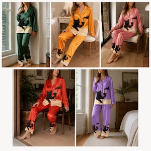 May include: A set of long-sleeved button-down pajamas featuring a black cat graphic pouring wine from a bottle into a glass. The pajamas are available in green, orange, pink, red, and purple, each with a contrasting cream-colored hem detail.