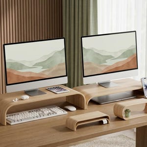 May include: Two light wood monitor stands with curved edges, a smaller rectangular wood stand, a small oval wood shelf containing a tiny potted plant, a white keyboard, a white computer mouse, a tablet, and a smartphone on a wood desk.