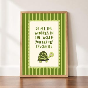 May include: A framed wall art print featuring a light green and dark green vertical striped background. The center contains a cream-colored rectangle with a scalloped border, the text "OF ALL THE WONDERS IN THE WORLD YOU ARE MY FAVOURITE", and a turtle.