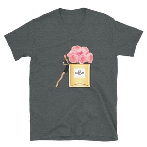 May include: Dark gray t-shirt featuring a graphic of a perfume bottle with pink roses, a woman in a black dress, and the text "N&deg;5 PARFUM PARIS". The design is centered on the shirt.