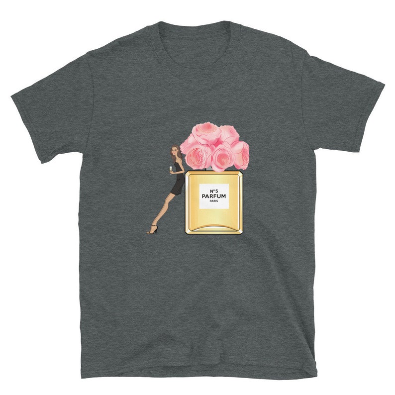 May include: Dark gray t-shirt featuring a graphic of a perfume bottle with pink roses, a woman in a black dress, and the text "N&deg;5 PARFUM PARIS". The design is centered on the shirt.