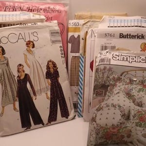Puede incluir: Una colección de patrones de costura variados de marcas como McCall's, Butterick y Simplicity. Los sobres de papel presentan ilustraciones de diversas prendas y artículos de decoración, con texto impreso, códigos de barras y números de modelo.