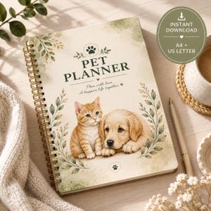 Puede incluir: Un cuaderno planificador de mascotas con encuadernación en espiral y cubierta color crema que presenta una ilustración en acuarela de un gatito atigrado naranja y un cachorro de golden retriever, rodeados de hojas verdes y el texto PET PLANNER Plan with love.