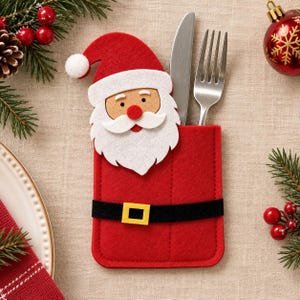 May include: A red felt cutlery holder shaped like a Santa Claus suit, featuring a white beard, a red hat with a white pom-pom, and a black belt with a yellow buckle. A silver metal knife and fork are tucked inside the rectangular pocket.
