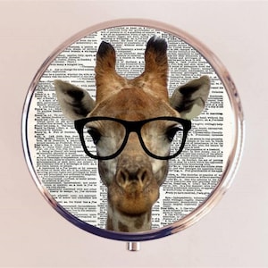 May include: A round, silver compact mirror with a black and white printed design of a giraffe wearing glasses. The giraffe's face is centered in the mirror and the background is a black and white print of text.
